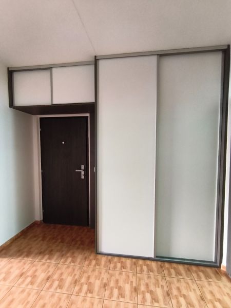 Entrance hall in a 3-room apartment with wood-patterned flooring and a built-in wardrobe.