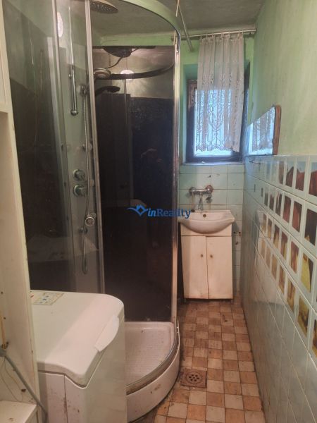 A bathroom in a family house with a corner shower and tiled floor.