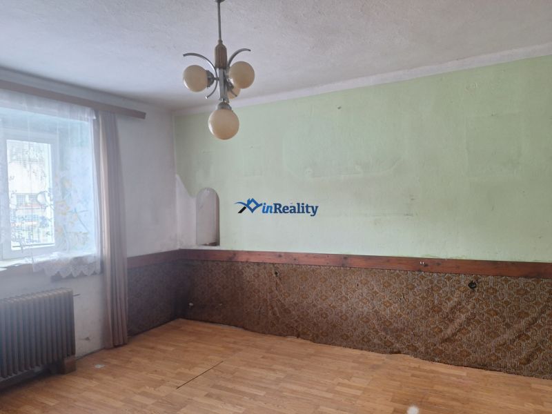Interior of a family house with a green wall, wood-patterned flooring, and curtains.