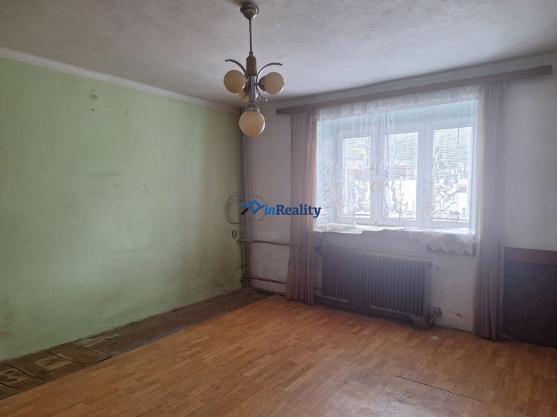 A room with a wooden floor decor, a window with a radiator, a light wall, a family house.