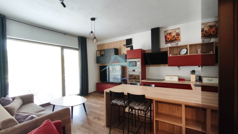 A kitchen in a 2-room apartment with a wooden decor floor and modern furniture.