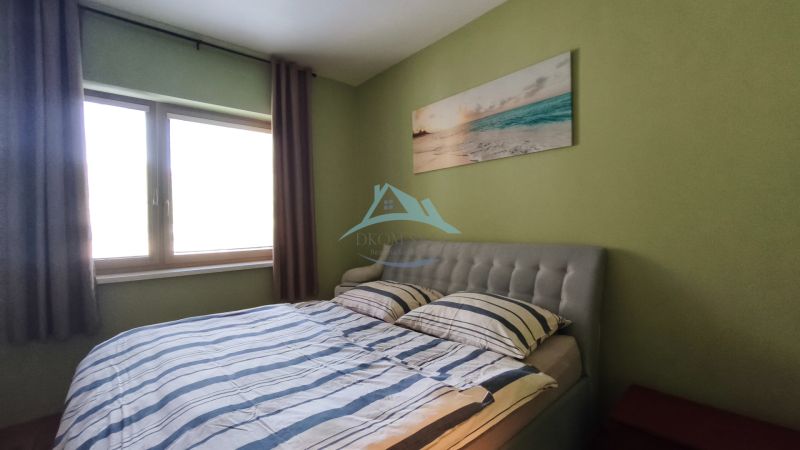 Bedroom with a bed, green walls, and a painting in a 2-room apartment.