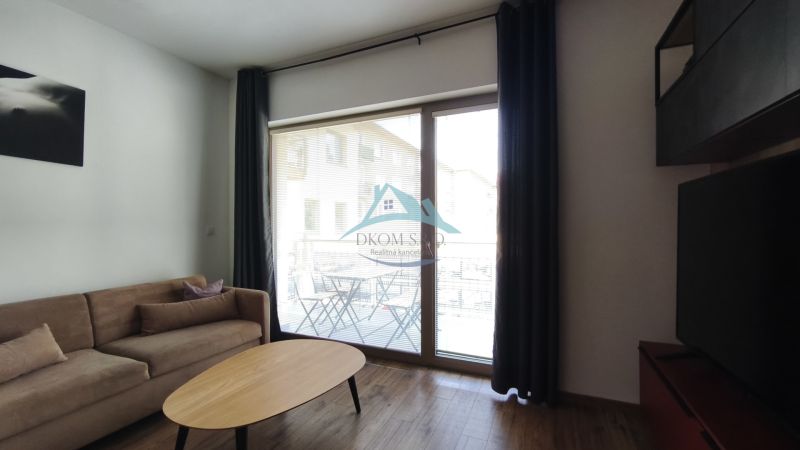 Living room with a sofa, wood-patterned floor, and a large window in a 2-room apartment.