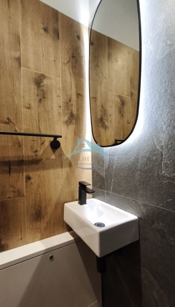 Bathroom with wood-patterned flooring, a mirror, and a small sink in a 2-room apartment.