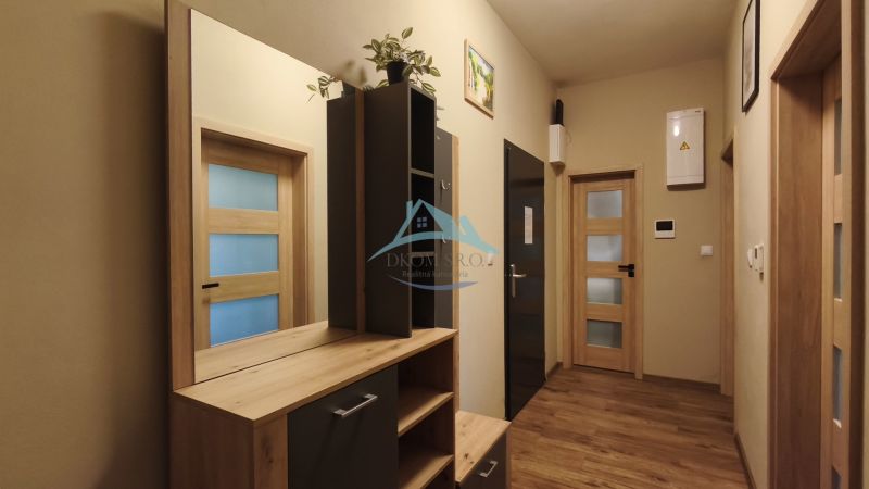 Entrance hallway in a 2-room apartment with a wooden decor floor and a built-in wardrobe.