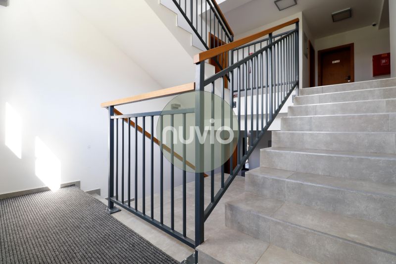 Staircase in a holiday apartment with tiles, railing, and carpet.