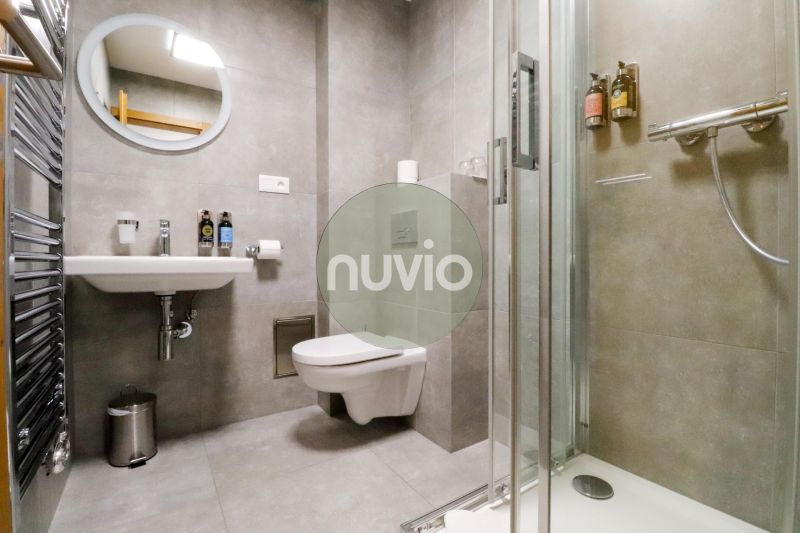 The bathroom of a holiday apartment with a sink, shower, and mirror.