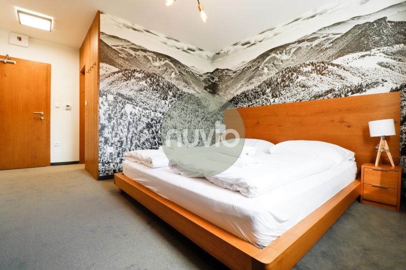 A bedroom in a holiday apartment with a wooden bed and a mountain photo wallpaper.