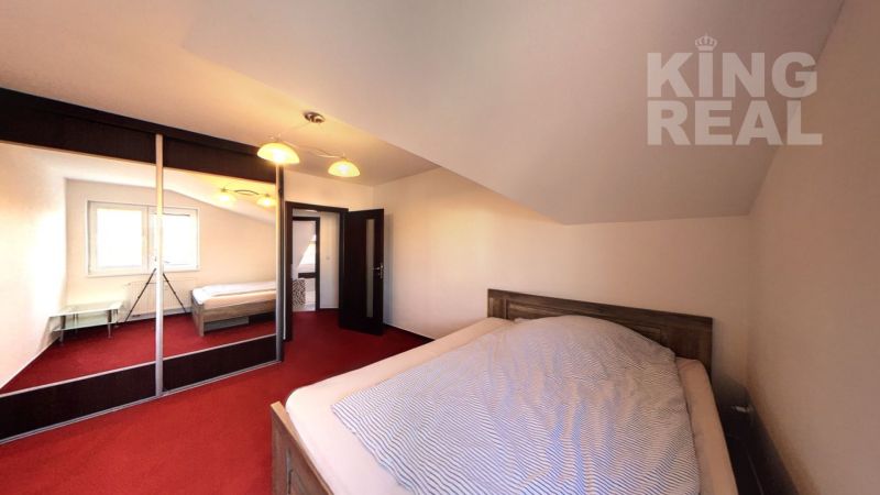 A bedroom in a two-room apartment with a red carpet and a built-in wardrobe.