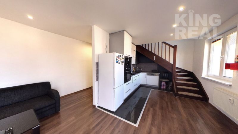 A kitchenette in a 2-room apartment with a wood-patterned floor and a sofa.
