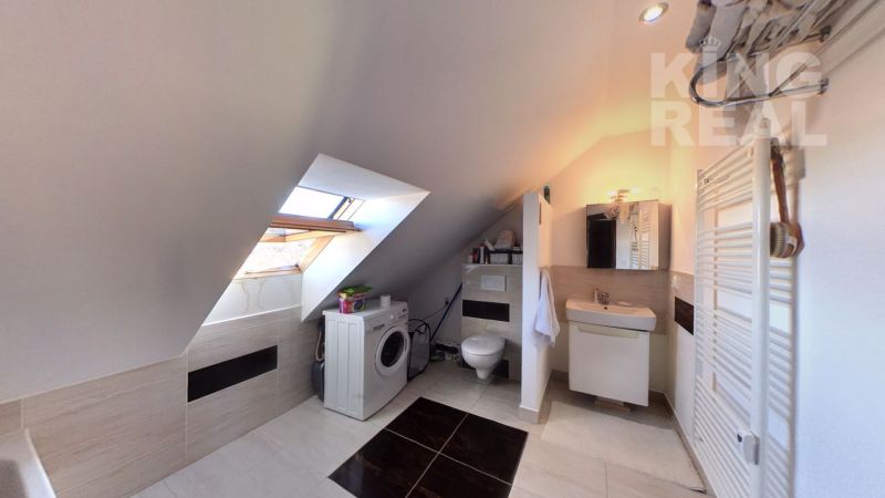 A bathroom under the roof in a 2-room apartment with a washing machine and a toilet.