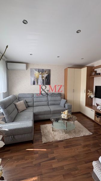 Living room in a 3-room apartment with a wooden decor floor and a comfortable gray sofa.