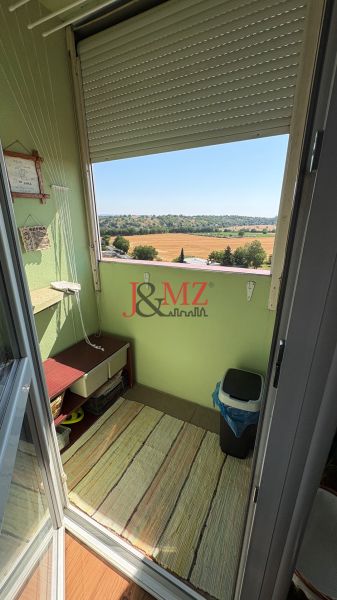 The balcony of a 3-room apartment in Levice with a view of fields and greenery.