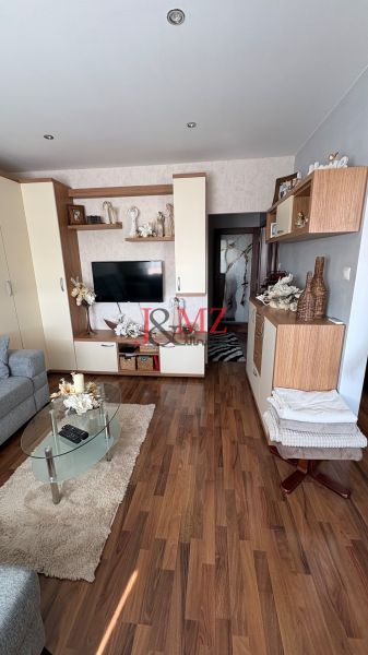 Living room with wood-patterned flooring in a 3-room apartment, cozy interior with decorations.