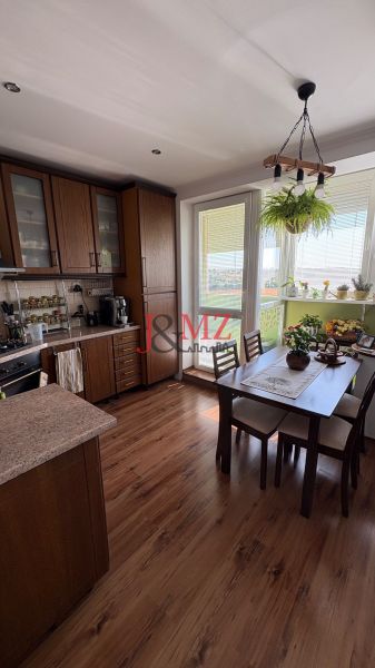 A kitchen in a 3-room apartment with a wood-patterned floor and a dining table.