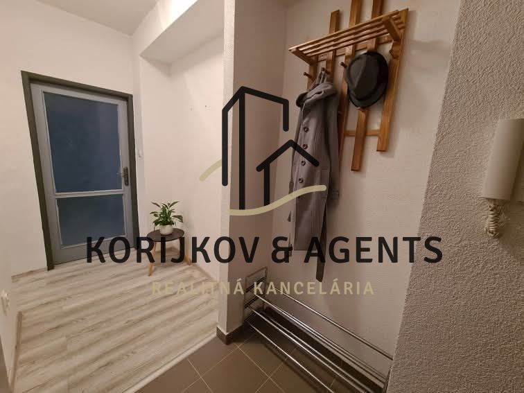 Entrance hallway in a 2-room apartment with a coat rack and flooring with a wooden decor.
