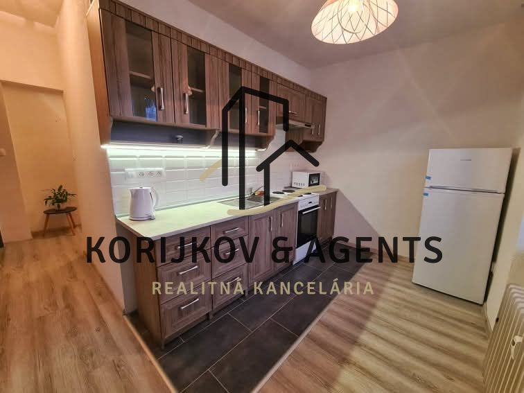 A kitchen in a 2-room apartment with a wooden floor decor and a kitchen unit.