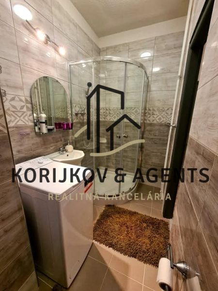 A bathroom with a washing machine and a shower in a 2-room apartment.