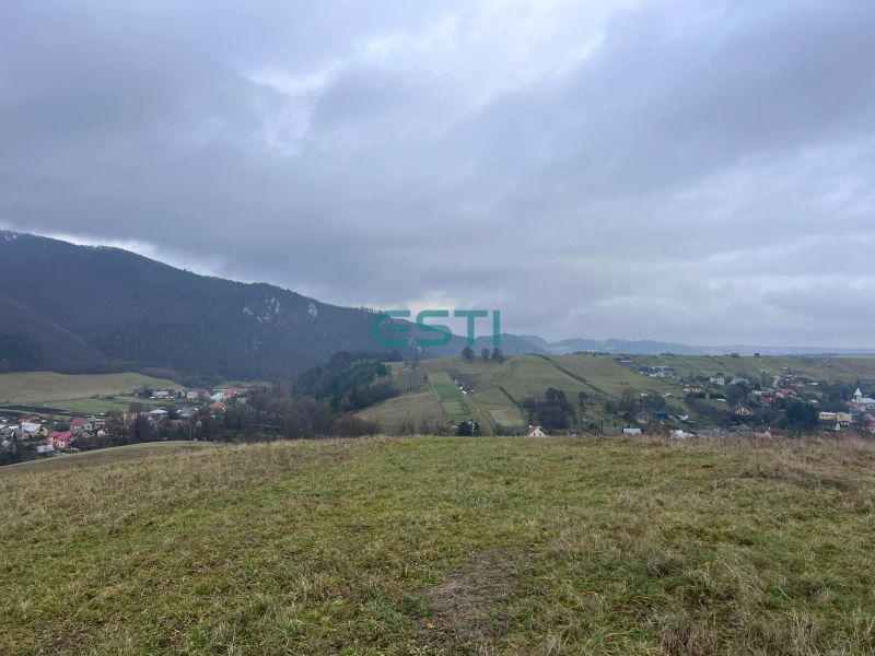 A view of agricultural and forest lands in Stránske with hills and a village.