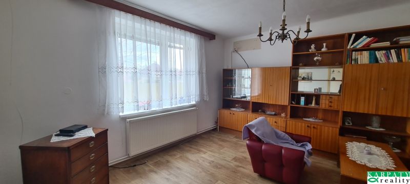 Living room with an armchair, shelves, and a wooden decor floor in a family house.