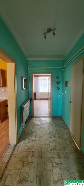 A hallway in a family house with turquoise walls and linoleum flooring.