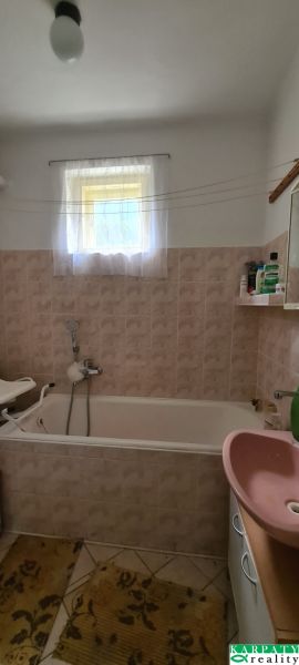 Bathroom with a bathtub, sink, and small window in a family house.