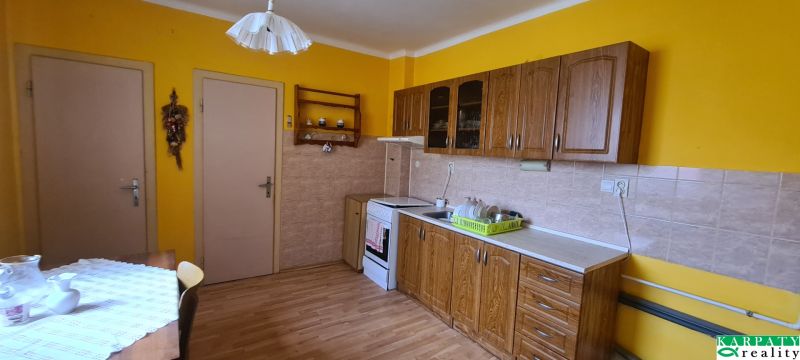 A kitchen in a family house with wooden decor, yellow walls, and a dining table.