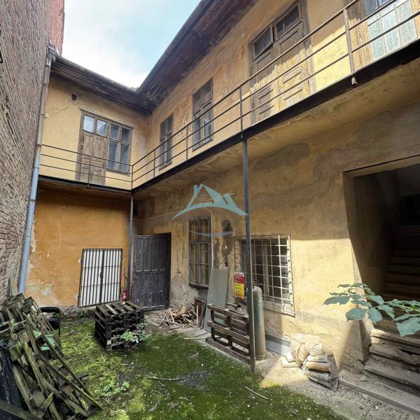 A courtyard of commercial spaces with worn plaster and plants in Šahy on the Main Square.