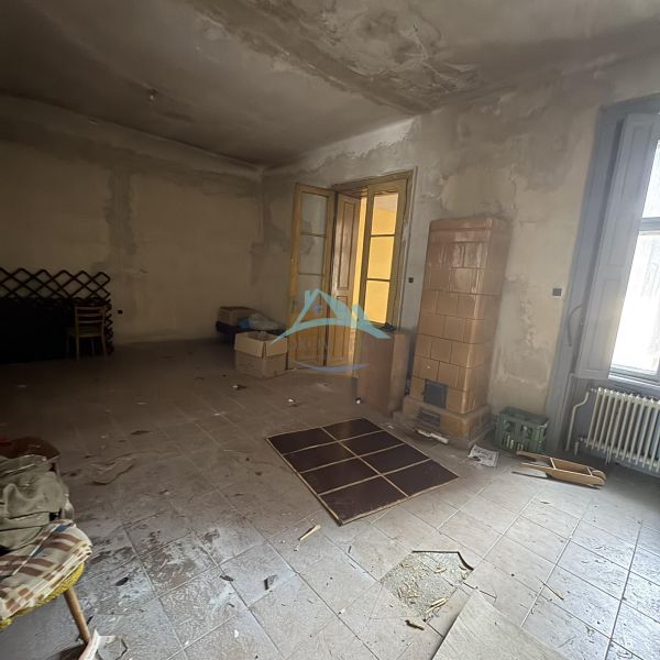 Abandoned commercial spaces with a tiled stove and large French doors.