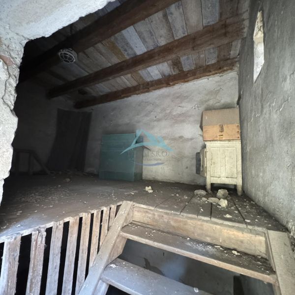 Interior of commercial premises with a wooden ceiling, stairs, and storage items.