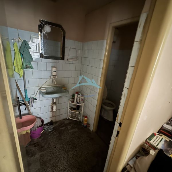 Bathroom with a sink, mirror, toilet, and cleaning products in commercial premises.