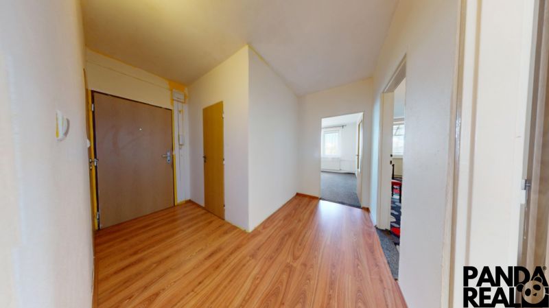 Entrance hall in a 3-room apartment with wood-patterned flooring and white walls.
