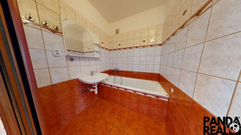 A bathroom in a 3-room apartment with a bathtub, sink, and tiles in warm tones.