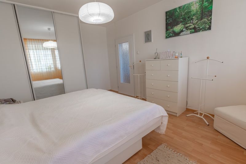 A bedroom in a 3-room apartment with white furniture and a floor with a wood decor.