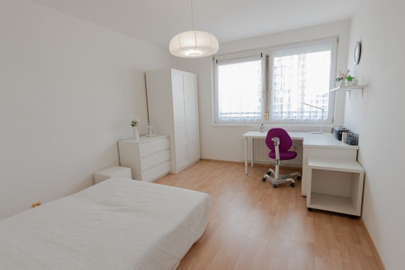 A bright bedroom with white furniture and a wooden decor floor in a 3-room apartment.