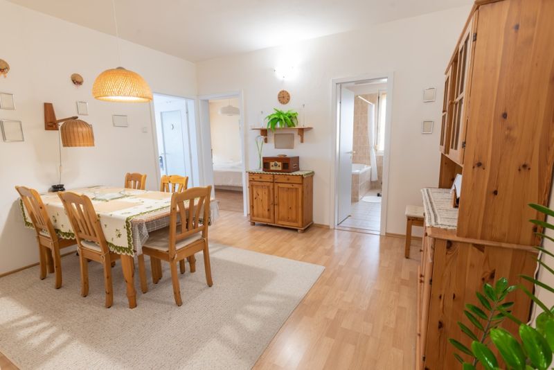 A bright dining room in a 3-room apartment with wooden furniture and a wood-patterned floor.