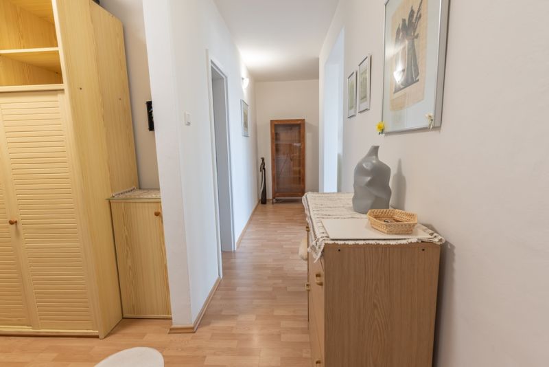 A hallway with a wood-decor floor and wooden furniture in a 3-room apartment.