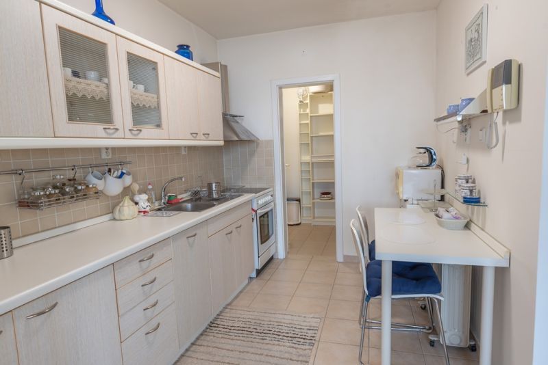 A kitchen in a 3-room apartment with a kitchen unit, dining table, and folding shelves.