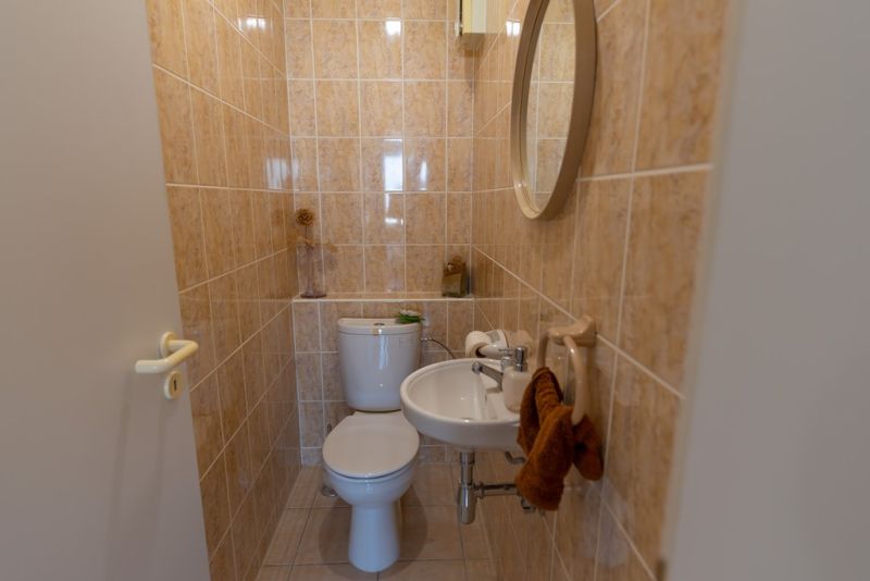 Bathroom in a 3-room apartment with a mirror, sink, and toilet in beige tiles.