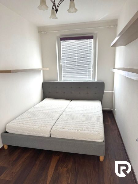A bedroom in a 3-room apartment with a comfortable bed and shelves, wooden decor flooring.