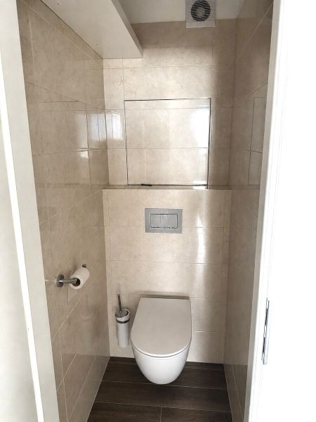 A toilet with a wooden decor floor in a 3-room apartment.