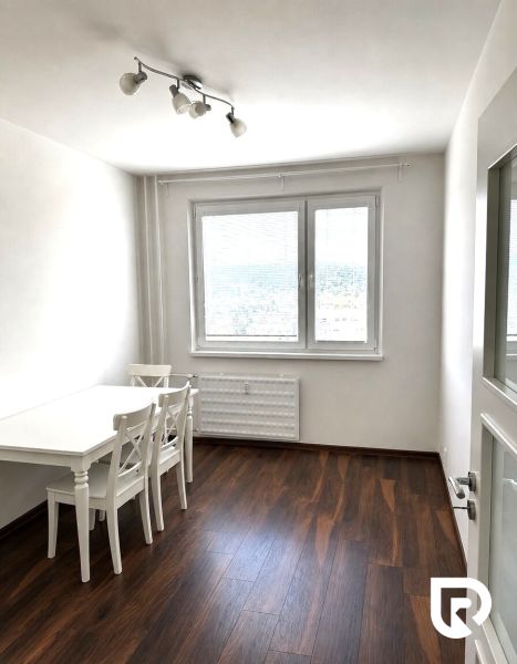 Bright dining room in a 3-room apartment with a white table and wood-patterned flooring.