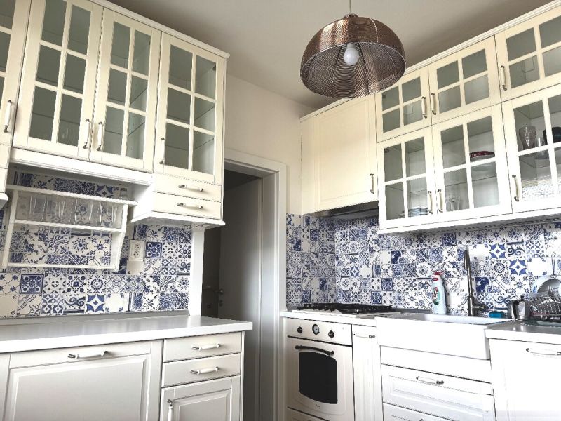A kitchen unit with glass cabinets and blue-white tiles in a 3-room apartment.