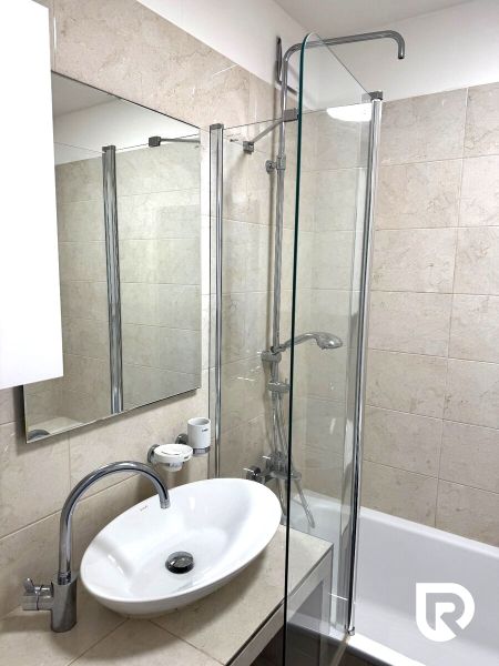Bathroom in a 3-room apartment with a bathtub and a sink, light tiles on the walls.