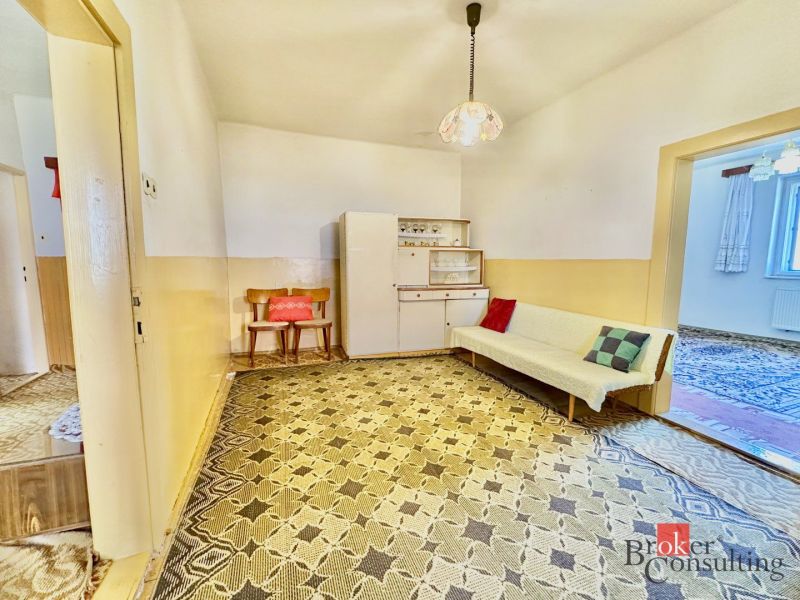 A room in a family house with a sofa, cabinet, and a retro carpet in decorations.