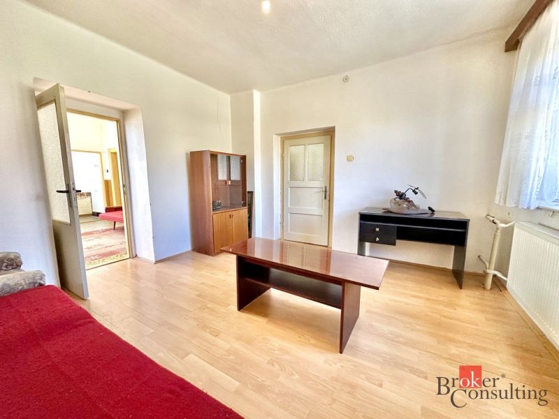 Living room in a family house with a wooden decor floor and simple furnishings.