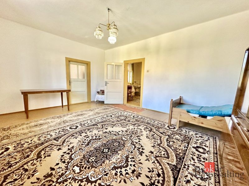 A family house with a large carpet, wooden table, and simple furniture.