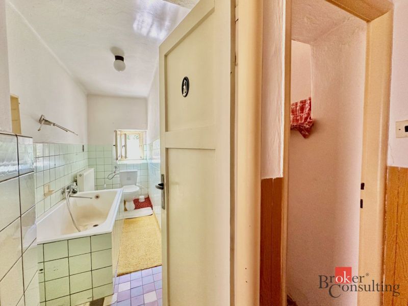 Bathroom in a family house with a bathtub, sink, and tiles.