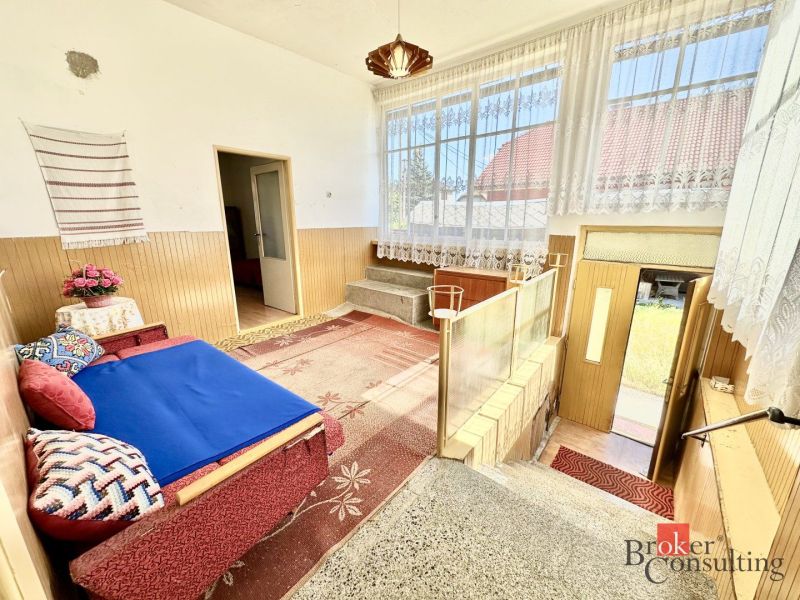 Interior of a family house with large windows and a floral sofa.