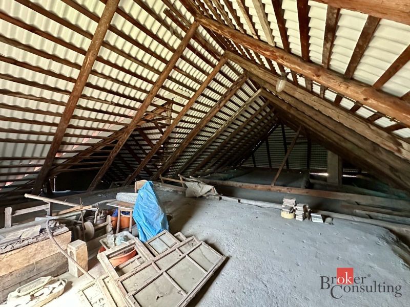 Attic in a family house with wooden beams, Kosorín, mess and various tools on the ground.